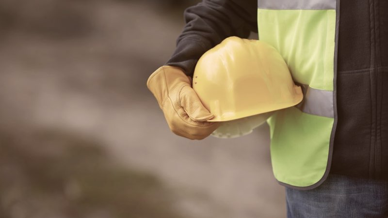 Construction worker holds his helmet while on the construction job site.