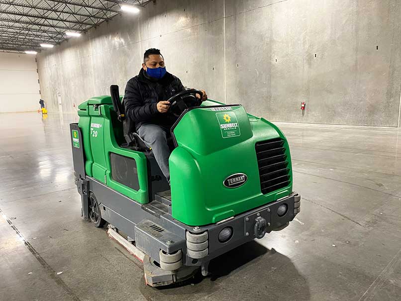 Better Cleaning Services warehouse floor cleaning in a ride along floor sweeper