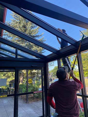 Man squeegee cleaning a window.