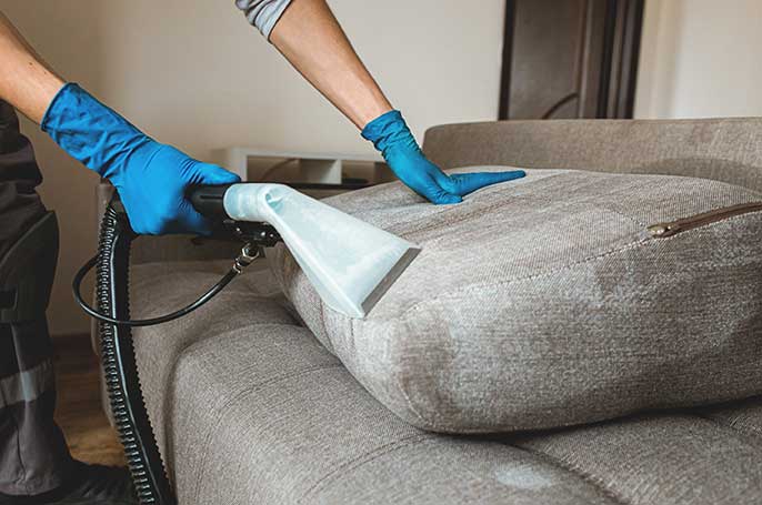 Man steam cleans dirty upholstery.