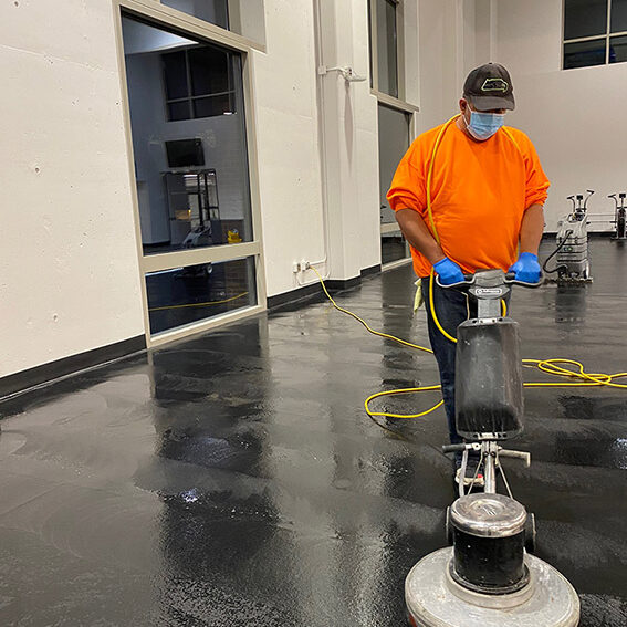 man machine scrubs rubber gym floor.